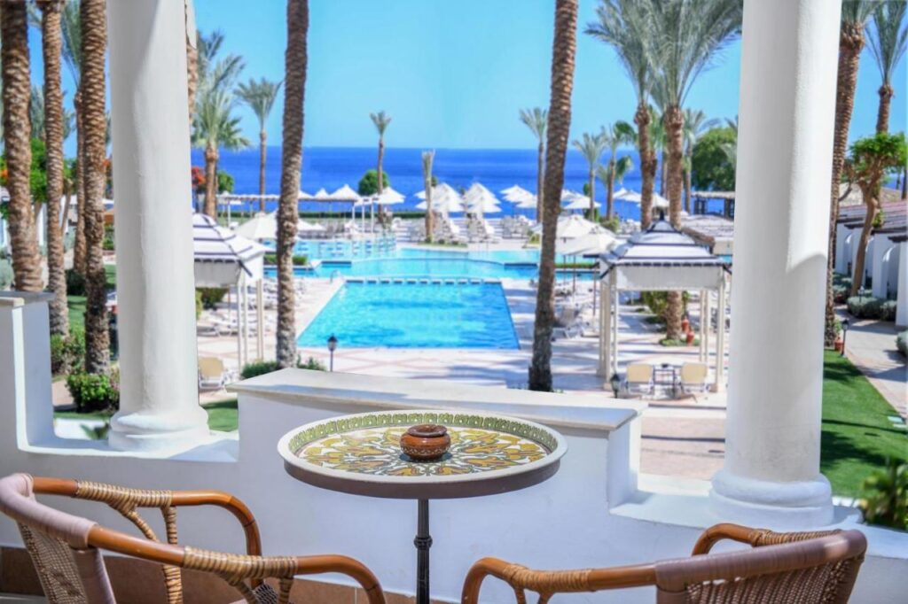 Výhled z terasy hotelu JAZ Fanara Resort na bazény, palmy a Rudé moře