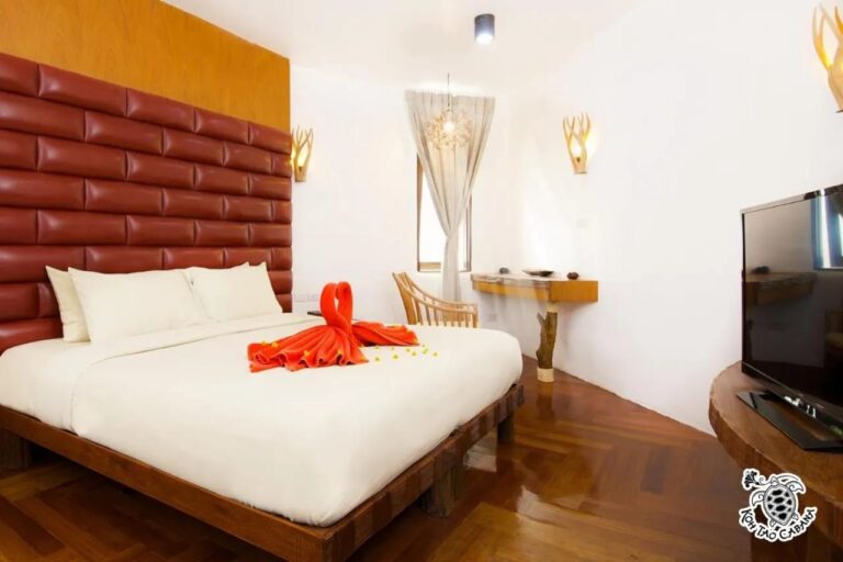 Bílý pokoj v resortu Koh Tao Cabana s manželskou postelí, červeným čalouněným čelem a televizí