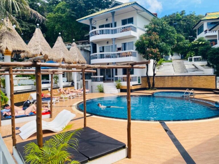 Bazén hotelu Koh Tao Heritage s lehátky a slaměnými slunečníky před budovou s balkony