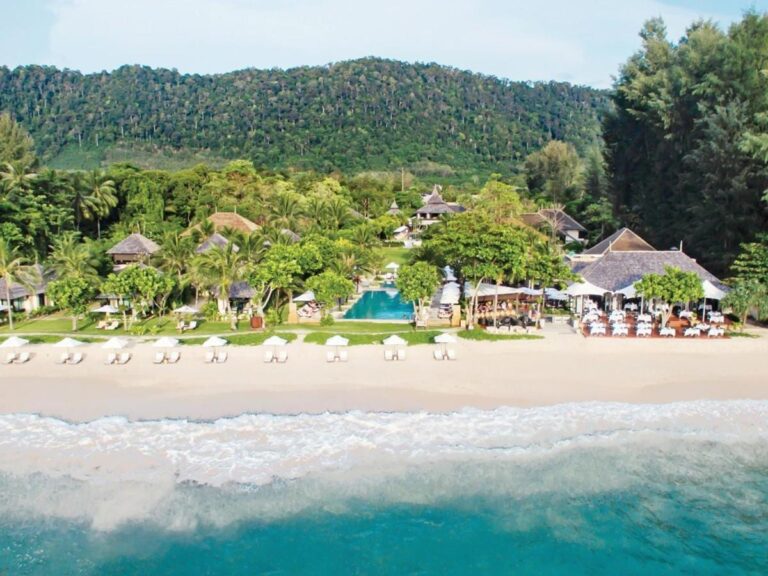 Layana Resort z moře, s pláží, bílými slunečníky, bazénem a střechami pod palmami