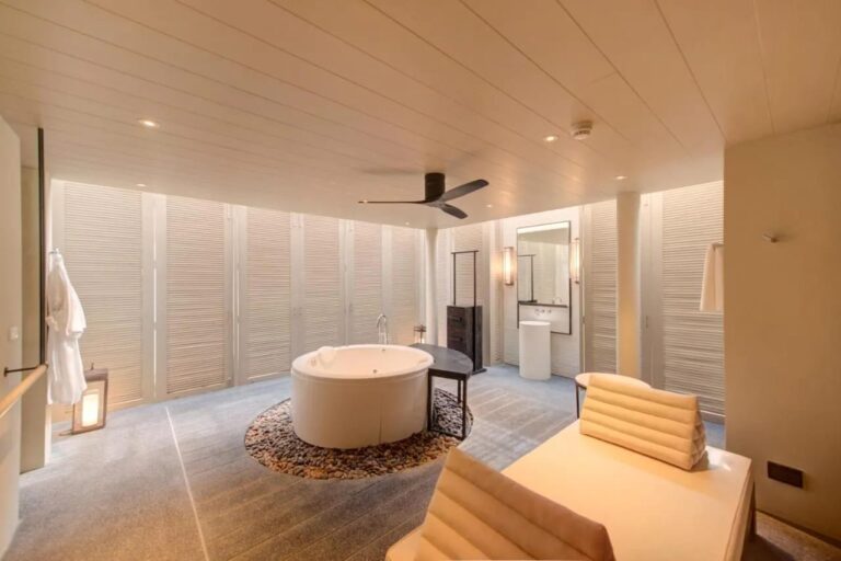 Koupelna v hotelu Layana Resort s kulatou vanou na oblázcích a zavěšeným županem