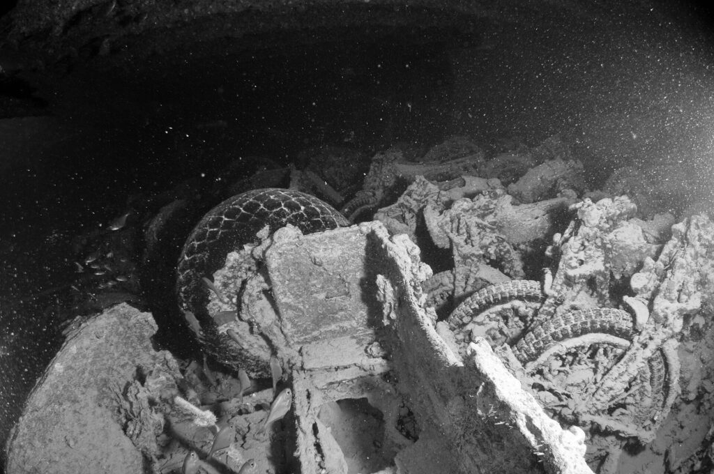 Motocykly naskládané v podpalubí vraku Thistlegorm, černobílá fotografie, pneumatiky a kola dosud viditelné
