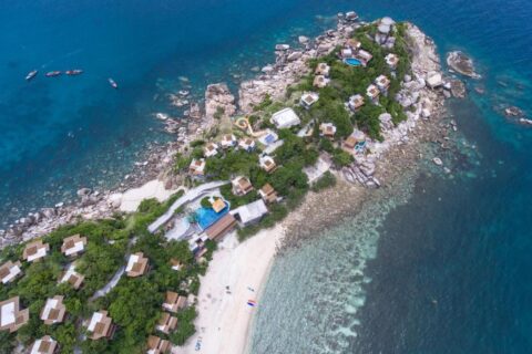 Letecký pohled na Sai Daeng Resort, jeho bungalovy na skalnatém výběžku, bazény a písečnou pláž