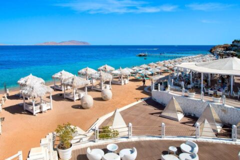 Pláž Sunrise Arabian Beach Resort se slaměnými slunečníky a molem, naproti ostrovu Tiran