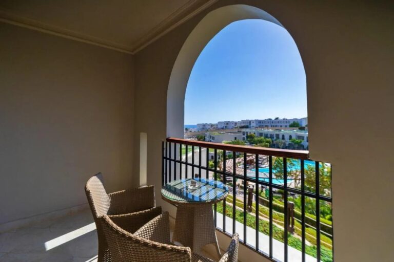 Balkon pod obloukem se dvěma pletenými křesly, nad bazény a zahradami